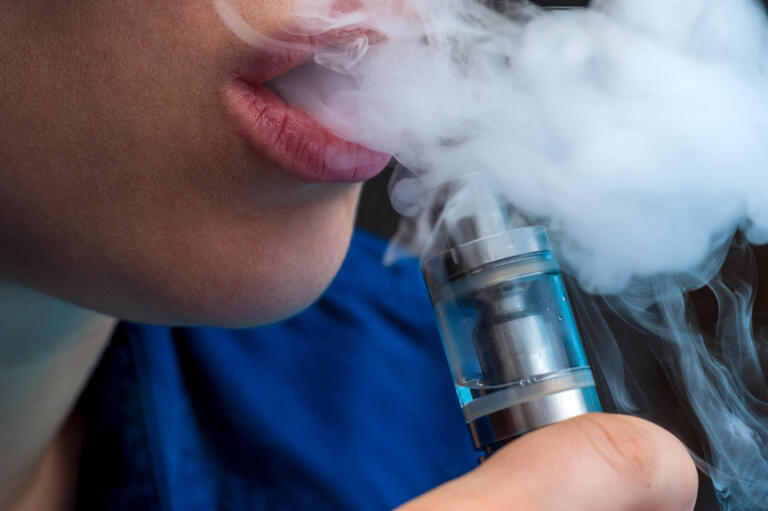 Close-up - young female vaping e-cigarette
